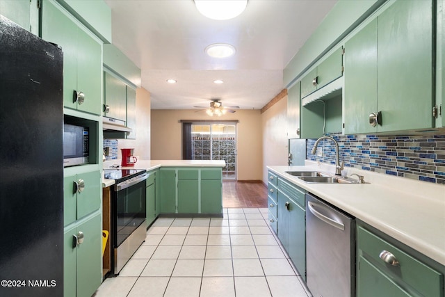 kitchen featuring appliances with stainless steel finishes, green cabinets, decorative backsplash, sink, and kitchen peninsula