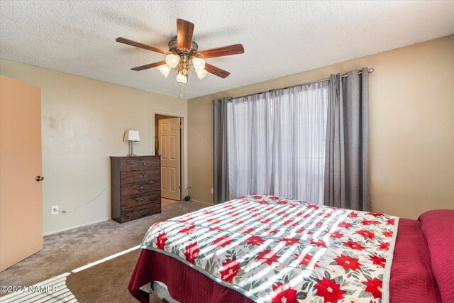 carpeted bedroom featuring ceiling fan and a textured ceiling