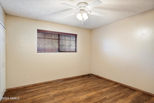 spare room featuring ceiling fan, dark wood-type flooring, and a textured ceiling