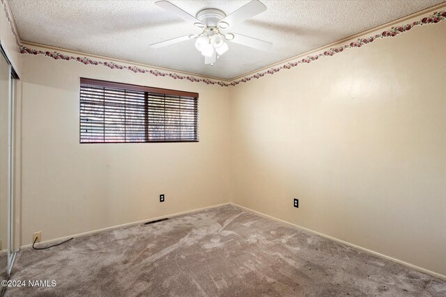 empty room with carpet flooring, a textured ceiling, and ceiling fan