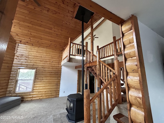 8120 N Cassity Trl, Williams, AZ 86046 - stairway featuring rustic walls, a towering ceiling, a wood stove, carpet flooring, and wooden ceiling