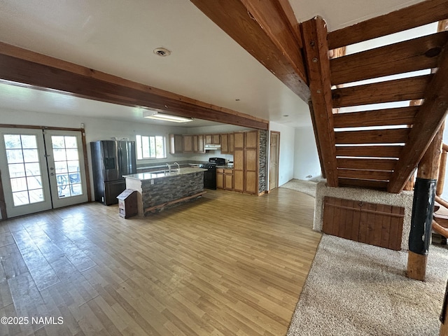8120 N Cassity Trl, Williams, AZ 86046 - kitchen with stainless steel refrigerator with ice dispenser, range, open floor plan, light wood-type flooring, and beamed ceiling