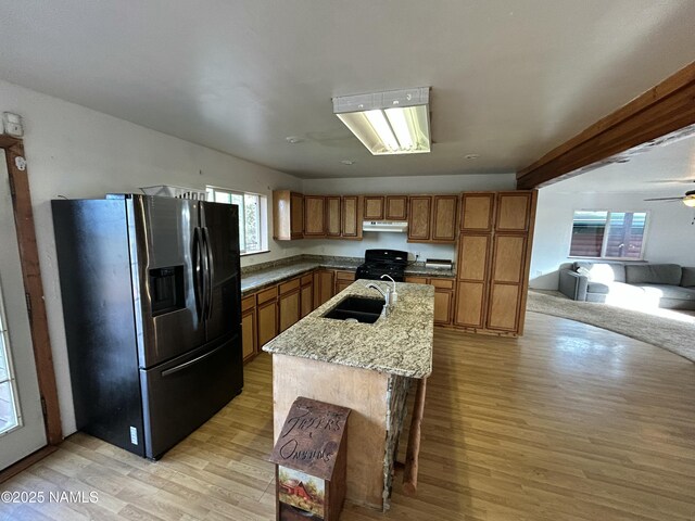 8120 N Cassity Trl, Williams, AZ 86046 - kitchen featuring black appliances, brown cabinets, light wood-style floors, a sink, and under cabinet range hood