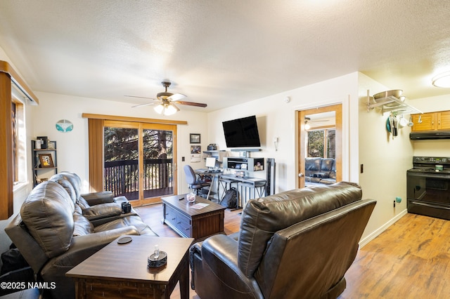 living room featuring light wood-type flooring, a textured ceiling, and ceiling fan