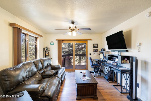 living room with ceiling fan, dark wood-type flooring, and a textured ceiling