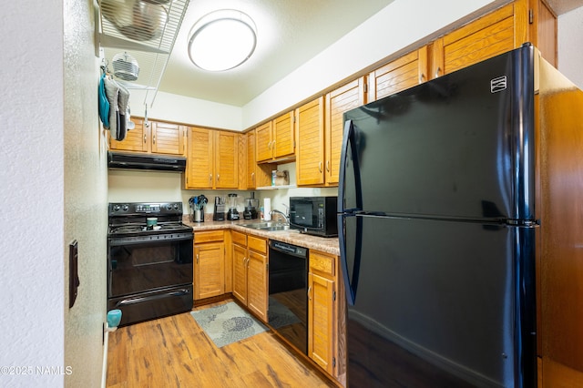 kitchen featuring black appliances, light wood-type flooring, and sink