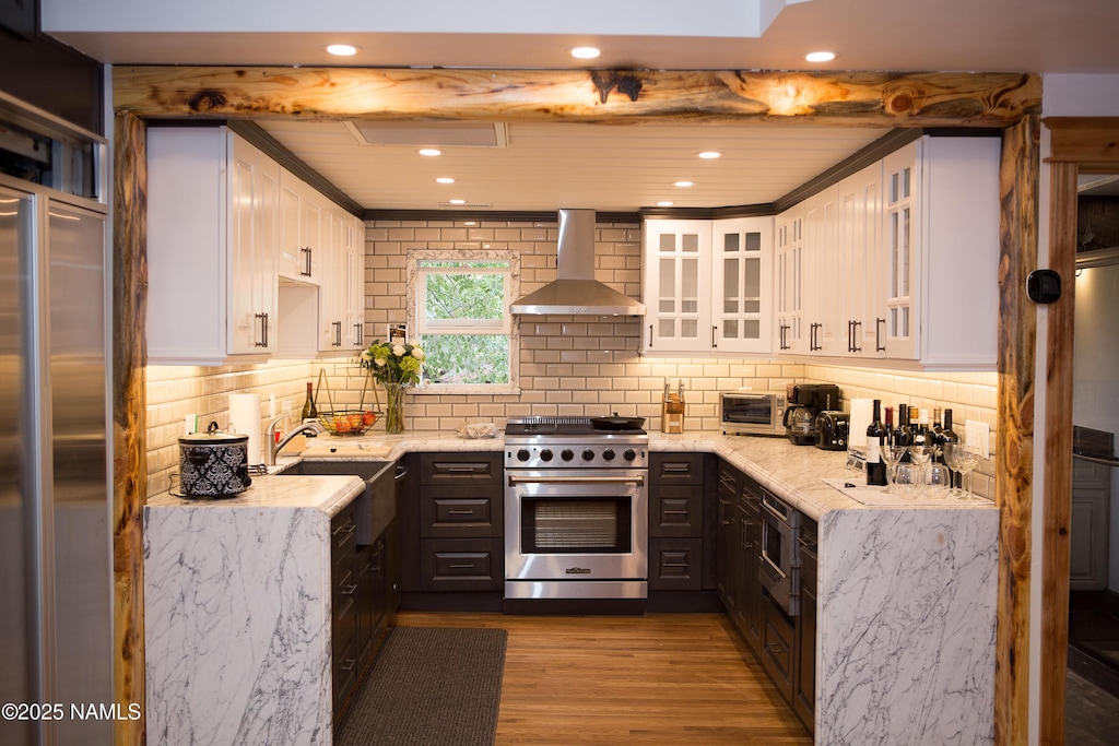 202 S Wc Riles St, Flagstaff, AZ 86001 - kitchen with wall chimney range hood, premium appliances, dark wood finished floors, decorative backsplash, and light stone counters