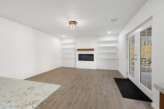 3540 N Walker St, Flagstaff, AZ 86004 - unfurnished living room with a glass covered fireplace, wood finished floors, baseboards, and french doors