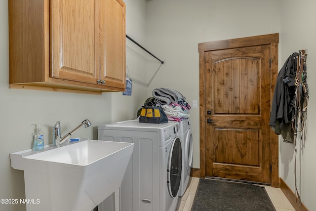 washroom featuring independent washer and dryer, cabinet space, a sink, and light tile patterned floors