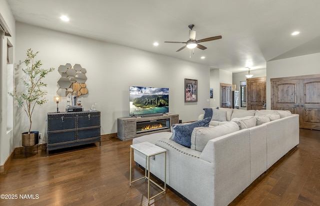 living room featuring recessed lighting, dark wood finished floors, and a glass covered fireplace