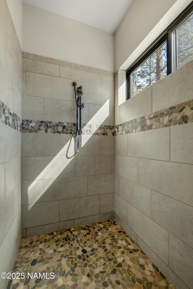 full bathroom featuring stone finish floor and tiled shower