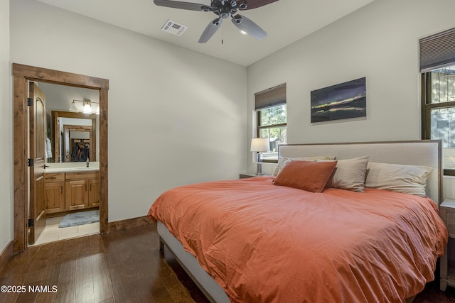 bedroom with visible vents, hardwood / wood-style floors, ensuite bathroom, a sink, and baseboards