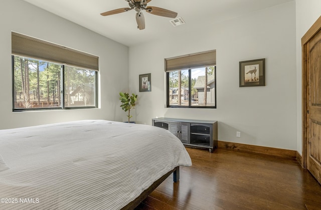 bedroom with a ceiling fan, wood finished floors, visible vents, and baseboards