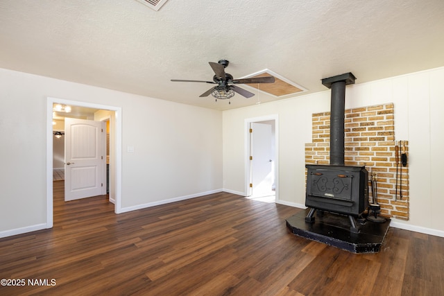 unfurnished living room with a wood stove, ceiling fan, dark hardwood / wood-style floors, and a textured ceiling