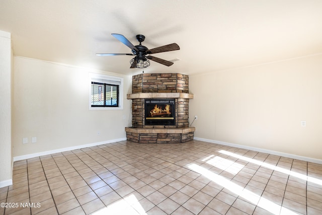 unfurnished living room with ceiling fan, light tile patterned floors, and a stone fireplace