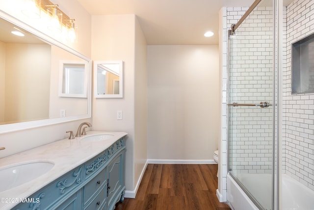 full bathroom featuring hardwood / wood-style floors, enclosed tub / shower combo, vanity, and toilet