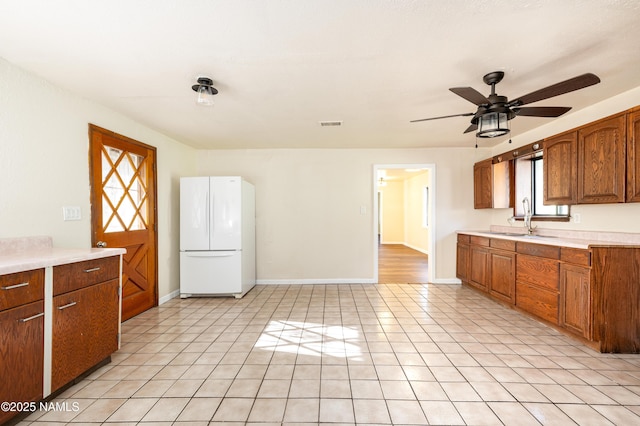 kitchen featuring sink, ceiling fan, light tile patterned floors, and white fridge