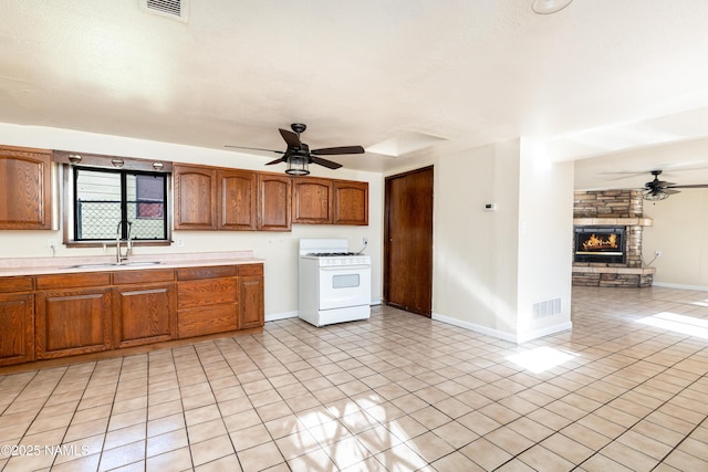 kitchen with ceiling fan, sink, white range with gas cooktop, and a fireplace