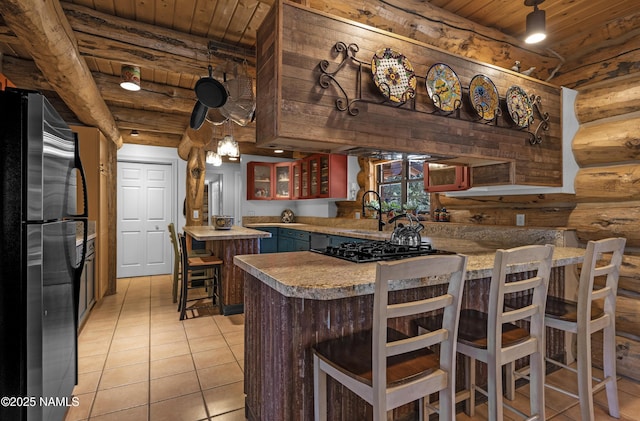 38 Cosnino Rd, Flagstaff, AZ 86004 - kitchen featuring freestanding refrigerator, wood ceiling, rustic walls, black gas cooktop, and light tile patterned flooring