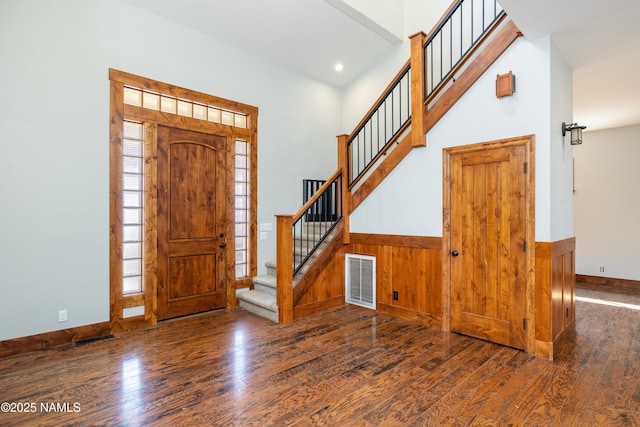 foyer featuring visible vents, wood-type flooring, a wainscoted wall, and stairway