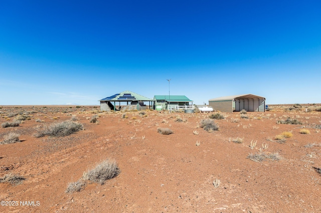 view of yard featuring a detached carport and dirt driveway