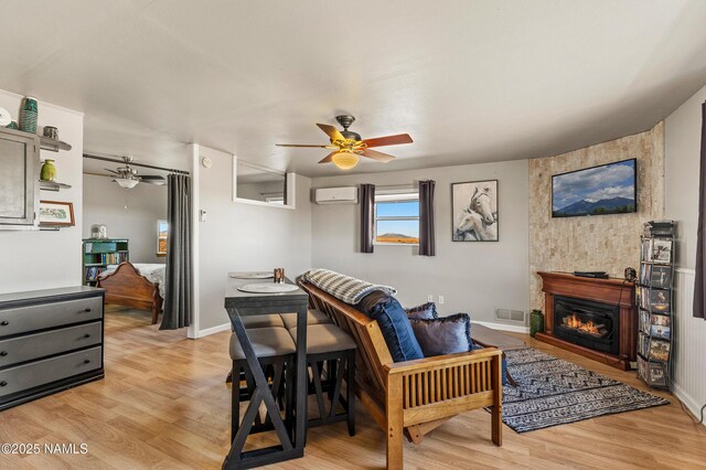 interior space with ceiling fan, a wall mounted AC, visible vents, and light wood-style floors