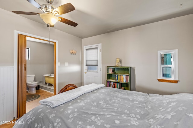 bedroom featuring multiple windows, a ceiling fan, wood finished floors, and ensuite bathroom