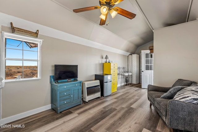 living room featuring ceiling fan, wood finished floors, baseboards, vaulted ceiling, and heating unit