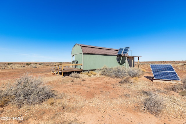 view of home's exterior with a gambrel roof and ground mounted solar panels