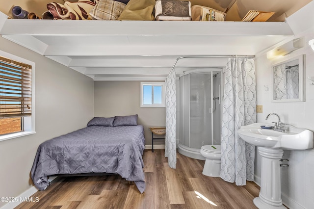 bedroom featuring wood finished floors, beam ceiling, and baseboards