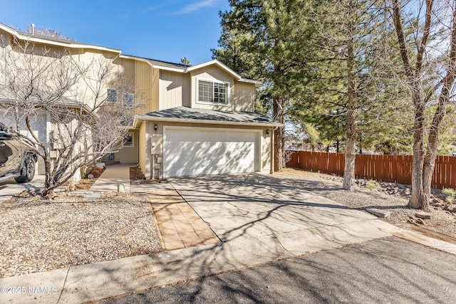 traditional-style home featuring a garage, concrete driveway, and fence