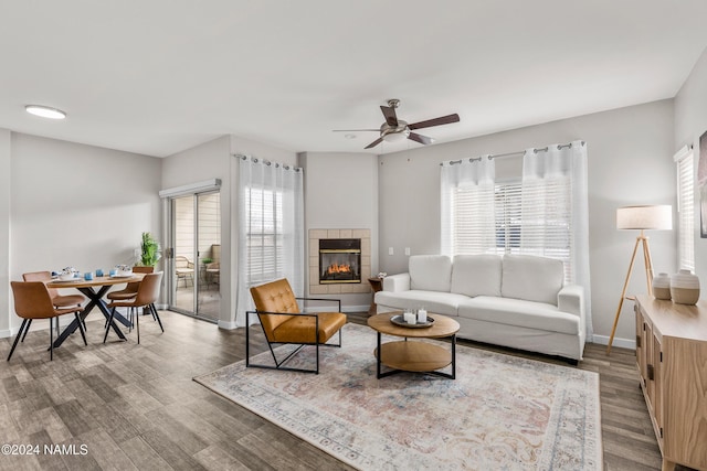 living room with wood-type flooring, a tile fireplace, ceiling fan, and a wealth of natural light