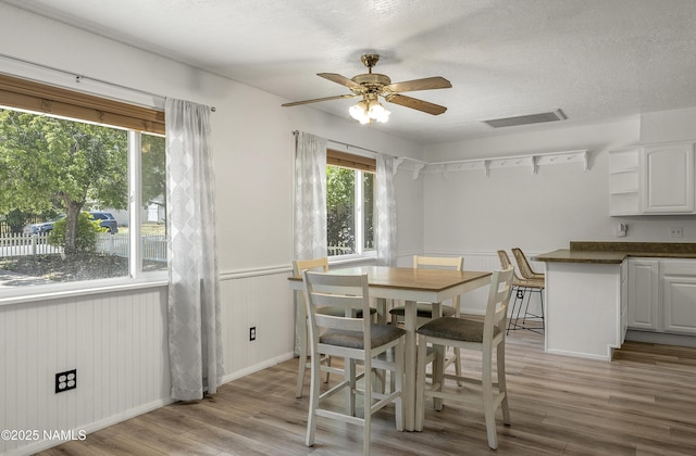 6320 N Mountaineer Rd, Flagstaff, AZ 86004 - dining space with light wood-style flooring, a wainscoted wall, a textured ceiling, and ceiling fan