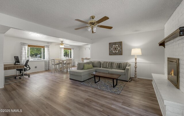 6320 N Mountaineer Rd, Flagstaff, AZ 86004 - living area featuring a textured ceiling, a desk, ceiling fan, wood finished floors, and a large fireplace