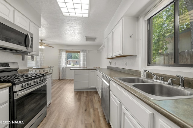 6320 N Mountaineer Rd, Flagstaff, AZ 86004 - kitchen featuring stainless steel appliances, white cabinetry, light wood-style flooring, ceiling fan, and a textured ceiling