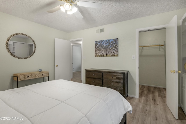 6320 N Mountaineer Rd, Flagstaff, AZ 86004 - bedroom featuring wood finished floors, a textured ceiling, a spacious closet, and a ceiling fan