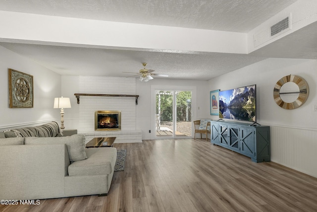 6320 N Mountaineer Rd, Flagstaff, AZ 86004 - living area with wood finished floors, a ceiling fan, a textured ceiling, and a fireplace