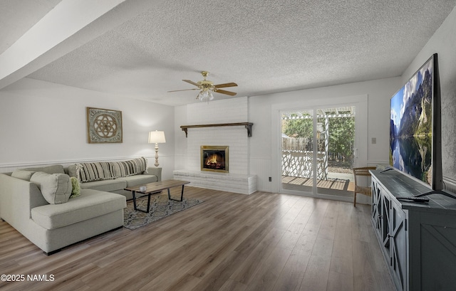 6320 N Mountaineer Rd, Flagstaff, AZ 86004 - living area featuring wood finished floors, a ceiling fan, a textured ceiling, and a fireplace
