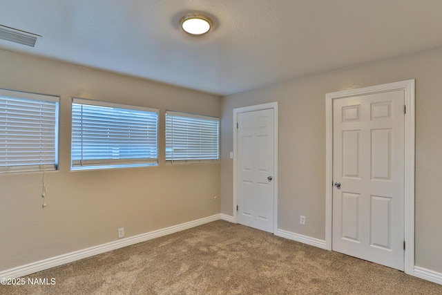 unfurnished bedroom with carpet flooring, visible vents, and baseboards