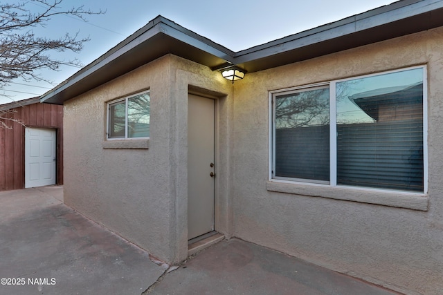 doorway to property featuring a patio area and stucco siding