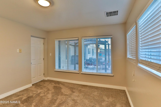 unfurnished room featuring carpet, visible vents, and baseboards