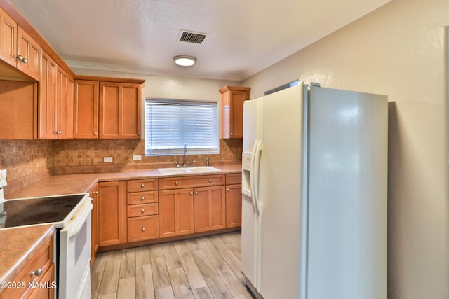 kitchen featuring white appliances, a sink, visible vents, light countertops, and backsplash