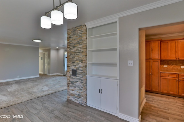 interior space with built in shelves, visible vents, baseboards, light wood finished floors, and crown molding