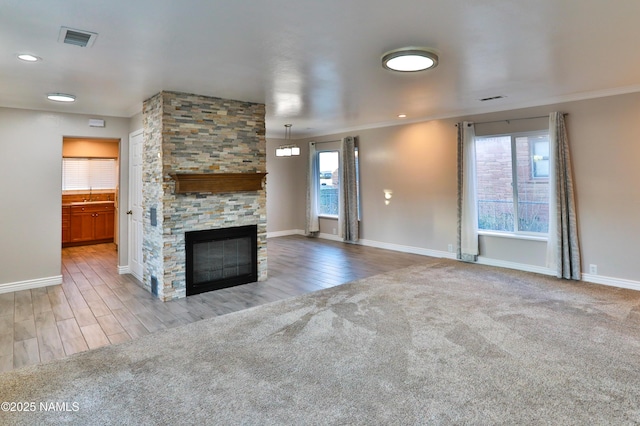 unfurnished living room featuring crown molding, carpet, visible vents, and a fireplace