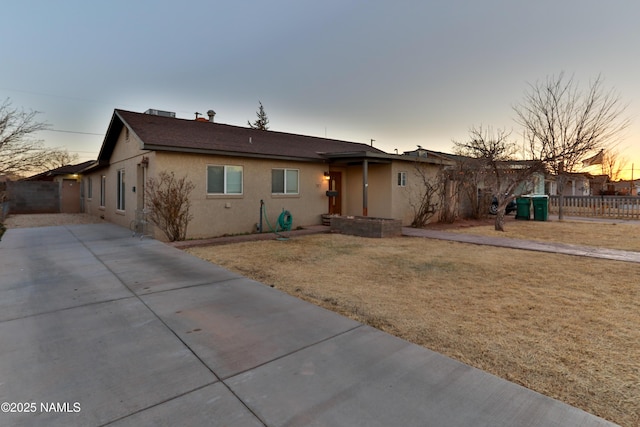 ranch-style home featuring a yard, fence, and stucco siding