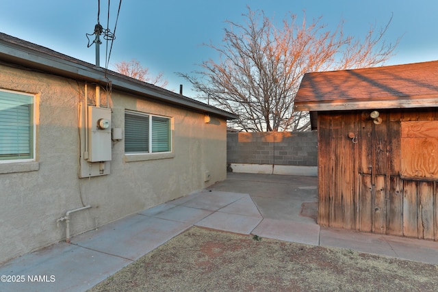 view of property exterior featuring a patio area, fence, and stucco siding