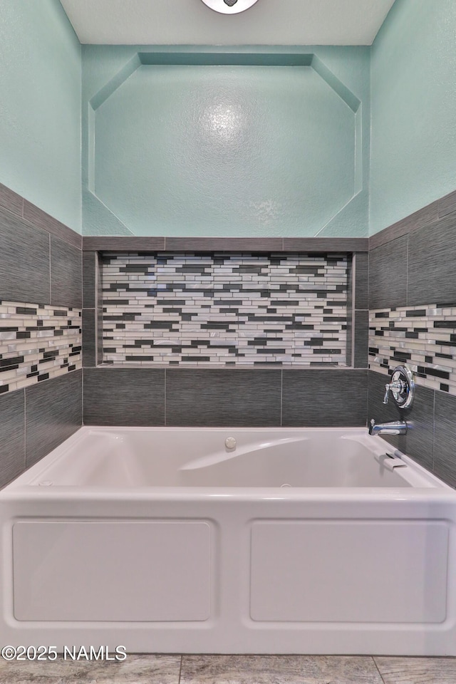 full bathroom with tile walls and a bath