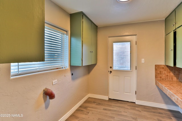 doorway featuring baseboards and light wood finished floors