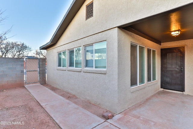 view of property exterior with fence, a gate, and stucco siding