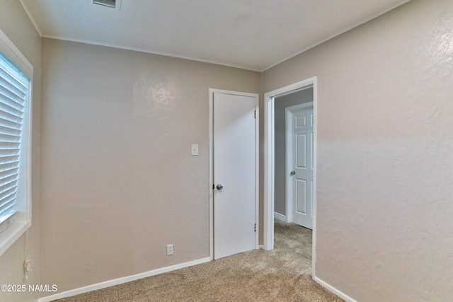 empty room with a textured wall, carpet, and baseboards